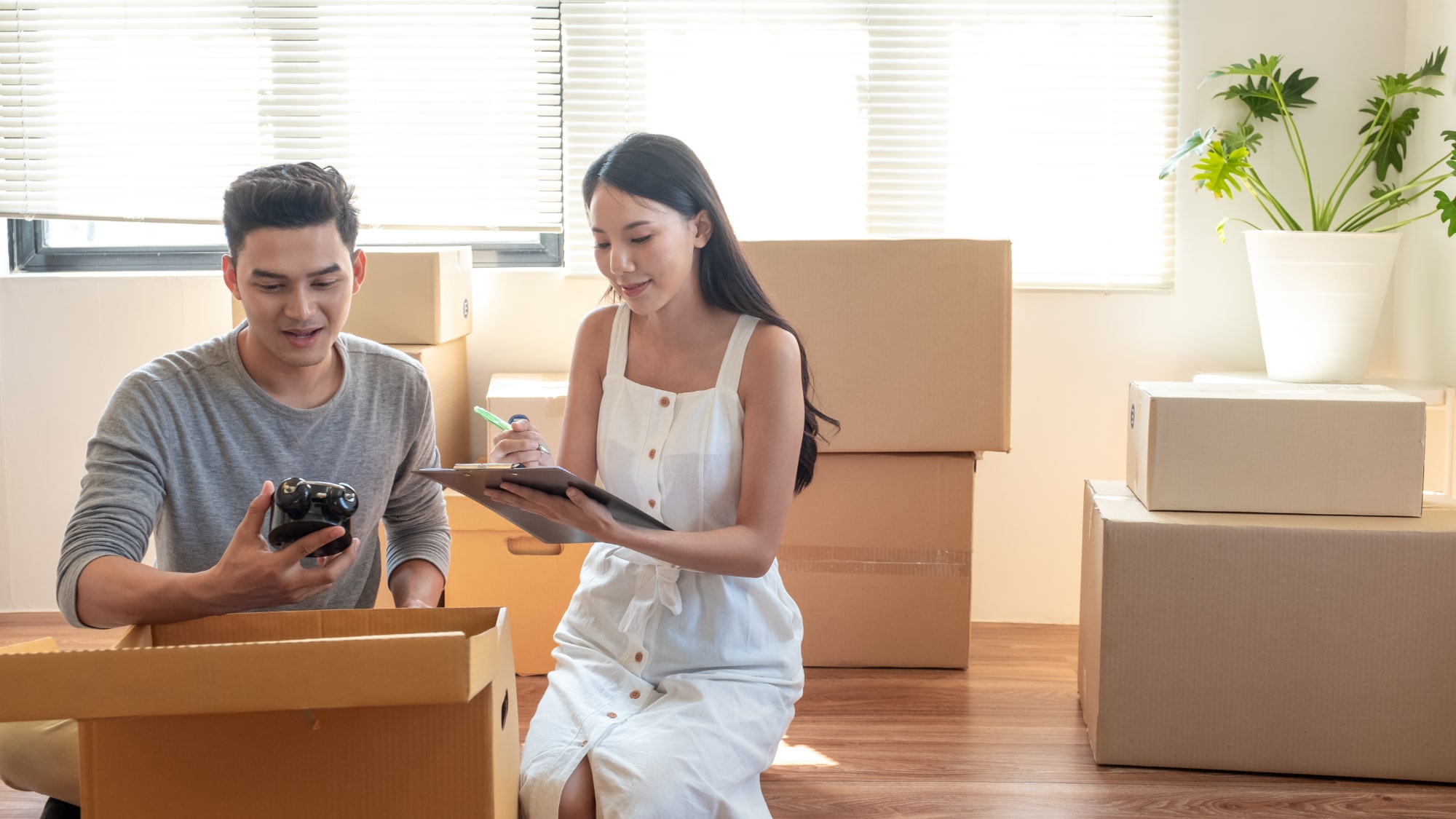 Asian couple surrounded by boxes with a moving checklist